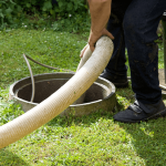 A man using a hose to drain a septic tank