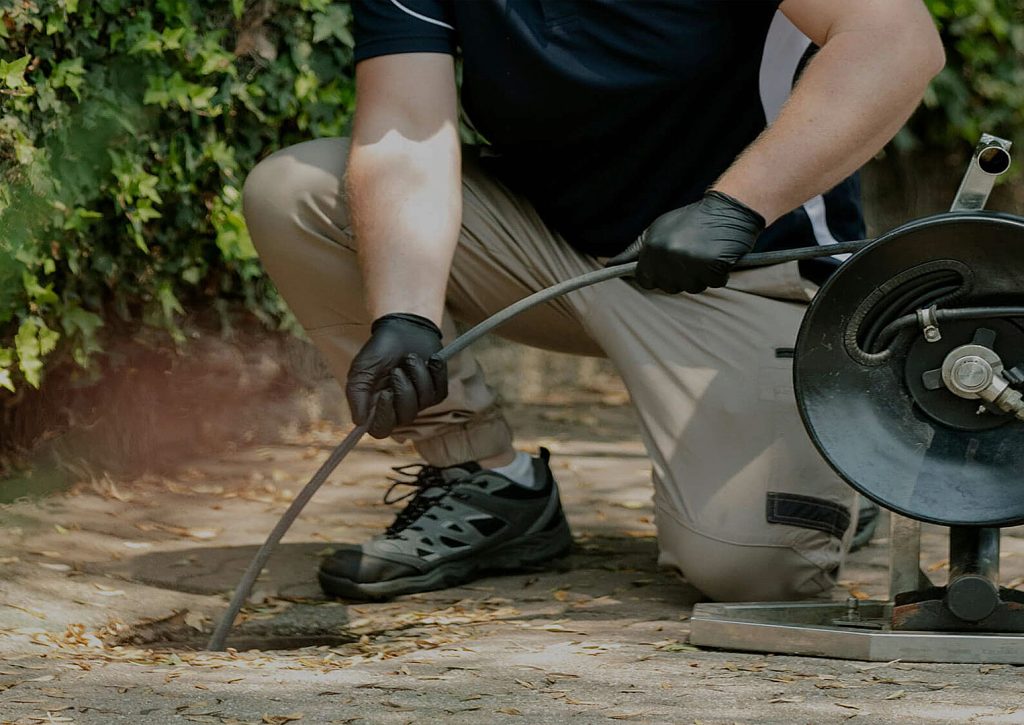 A man holding a camera or hose to inspect a drain
