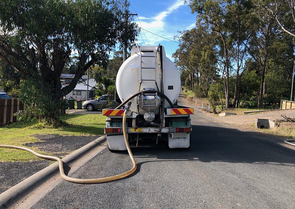 A truck with a hose parked outside on the road