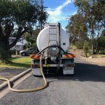 A truck with a hose parked outside on the road