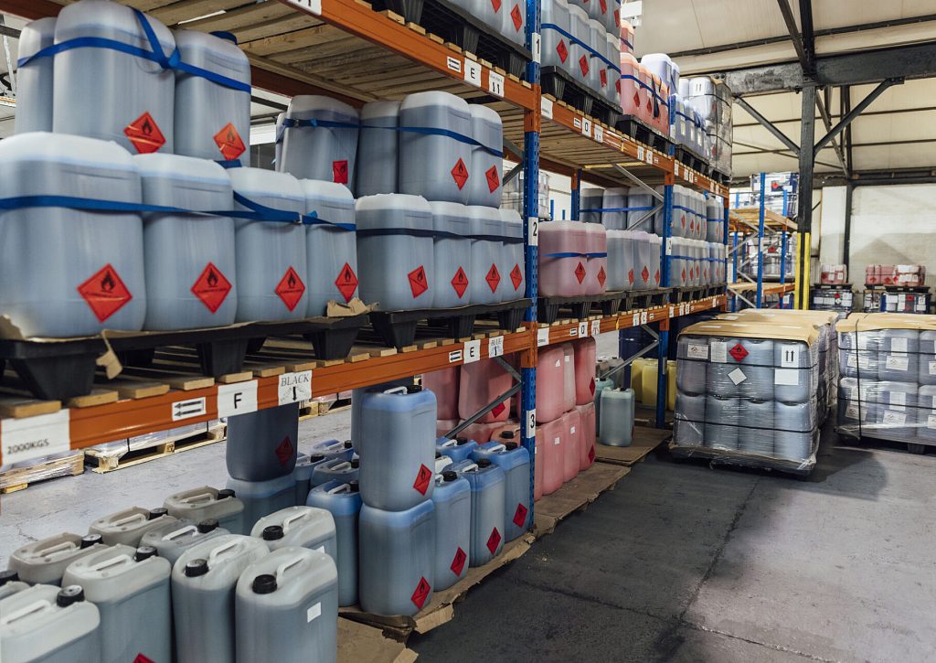 Multiple containers of hazardous waste stacked and stored inside a warehouse