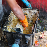 A person servicing a grease trap