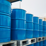 Rows of blue metal barrels, stacked up outside