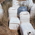 Discarded chemical containers and plastic drums stored outdoors, highlighting the need for safe chemical waste handling and disposal.