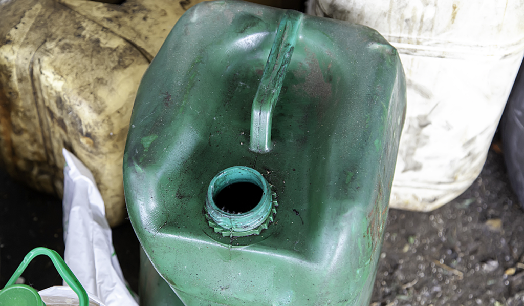 Used oil container with an open lid, showing a waste oil storage drum awaiting collection and disposal.