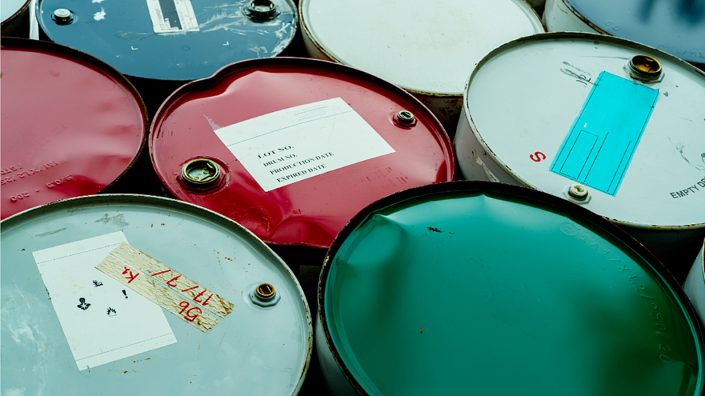 Steel drums containing waste oil and industrial liquids awaiting collection and recycling.