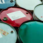 Steel drums containing waste oil and industrial liquids awaiting collection and recycling.