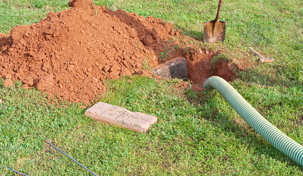 Septic pump out in progress with a vacuum hose connected to an underground septic tank.