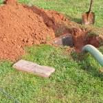 Septic pump out in progress with a vacuum hose connected to an underground septic tank.