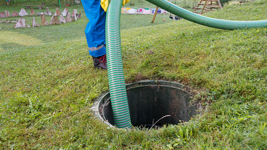 Technician pumping a residential septic tank through an underground access point.