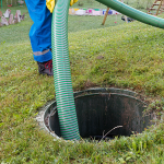 Technician pumping a residential septic tank through an underground access point.