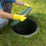 Technician opening a residential septic tank inspection cover for maintenance.