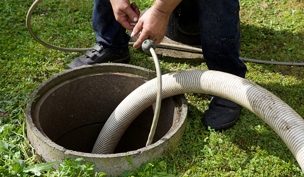 Technician pumping a septic tank using a vacuum hose