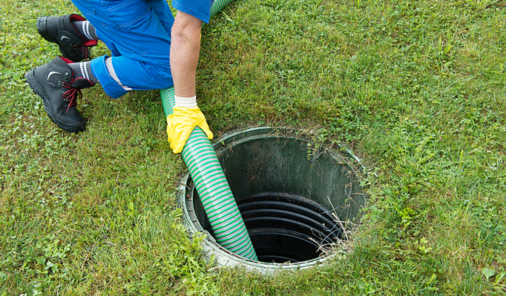 Worker pumping a septic tank with a vacuum hose