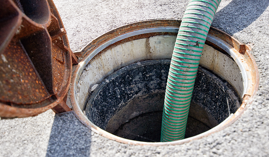 Commercial septic tank being pumped with a vacuum hose
