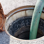 Commercial septic tank being pumped with a vacuum hose