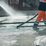 Workers pressure washing an industrial wash-down area